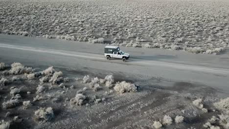 camión conduciendo en un camino de tierra en el desierto, seguimiento aéreo disparado zoom amplio