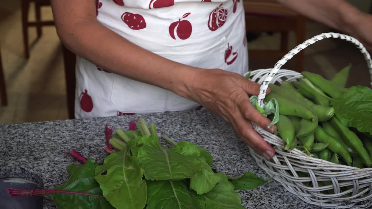mujer preparando acelgas frescas de cosecha propia y habas del jardín