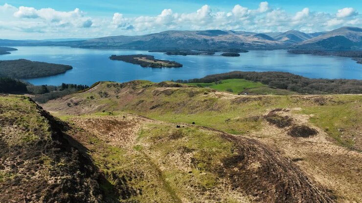 Vedute della Scozia, ripresa aerea cinematografica di una coppia che si affaccia sul Loch Lomond su Conic Hill in una soleggiata giornata di primavera