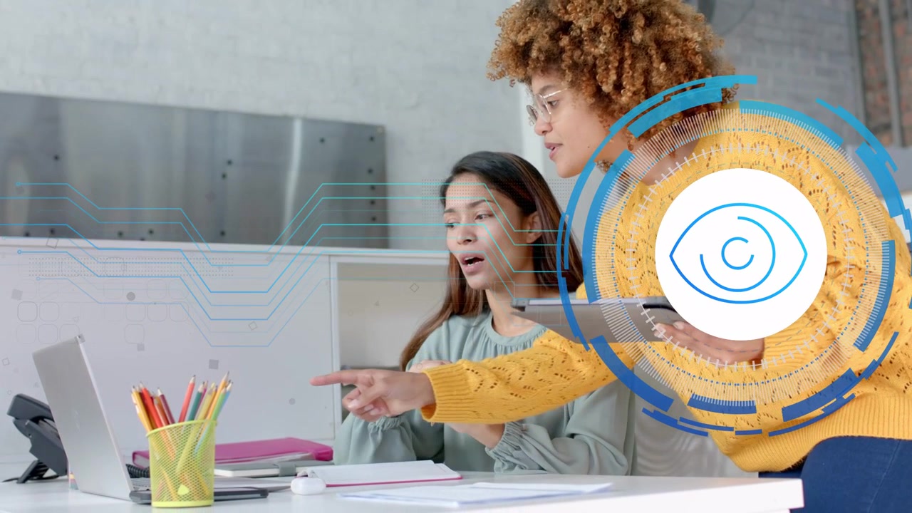 Seated woman gesturing as standing colleague holding tablet activating HUD, pointing laptop in tech