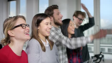 five good mooded people in a modern office doing a la ola wave together