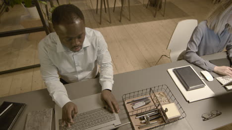 Top-View-Of-A-Serious-American-Employee-Working-On-Laptop-Computer-In-The-Office-1