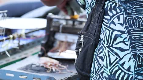 vendor grilling squid at a street food stall