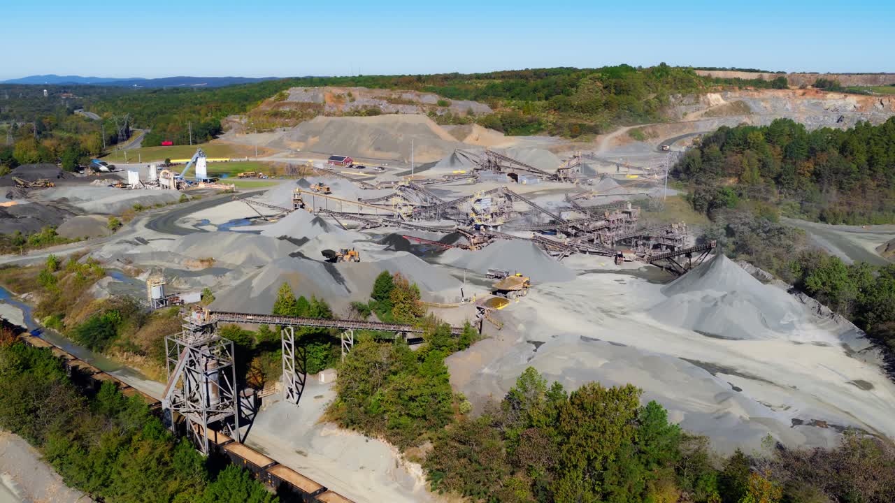 Wide aerial panoramic establishing of American quarry open pit mining operation with gravel piles and processing equipment