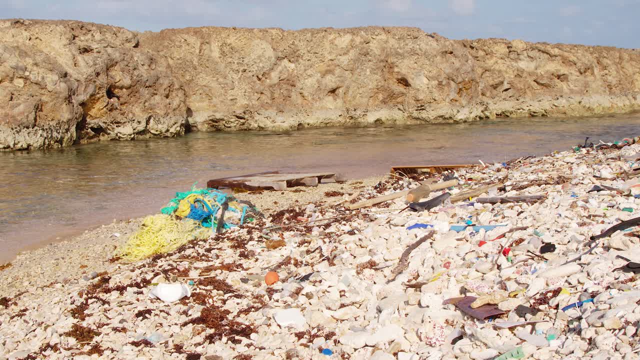 pan ancho de desechos plásticos hechos por el hombre y basura que se lavan lentamente en la costa rocosa en el caribe