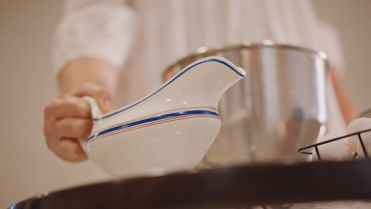 Scena di cucina. Preparazione: versare la salsa in una ciotola. Calda cucina autunnale con salsa versata nella ciotola per mescolare. Ampia inquadratura di una mano che versa la salsa in una ciotola in un'accogliente cucina autunnale.