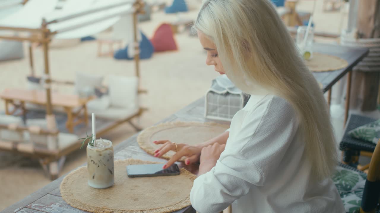 Woman using phone in beach cafe