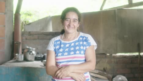 brunette woman looks at the camera outdoors and crosses her arms as she smiles, her smile telling stories of wisdom