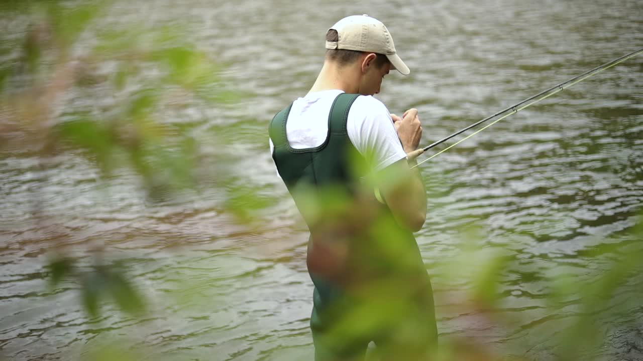 Rekaman Gerak Lambat seorang pemancing pria Kaukasia sedang menyiapkan kailnya saat fly fishing-1