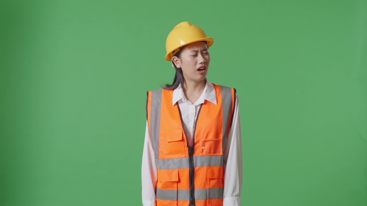 Wondering Asian Female Engineer With Safety Helmet Working Doubtfully In The Green Screen Background Studio
