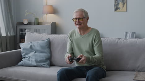 feliz anciano jugando videojuegos mientras se sienta en el sofá en casa 1