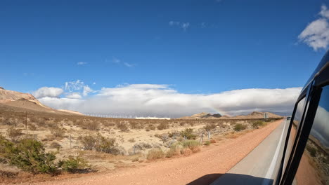 Fahren-Sie-Entlang-Einer-Autobahn-Und-Blicken-Sie-Zurück-Auf-Die-Trockene-Landschaft-Der-Mojave-Wüste---Bewegungshyperzeitraffer-Und-Wolkenlandschaft