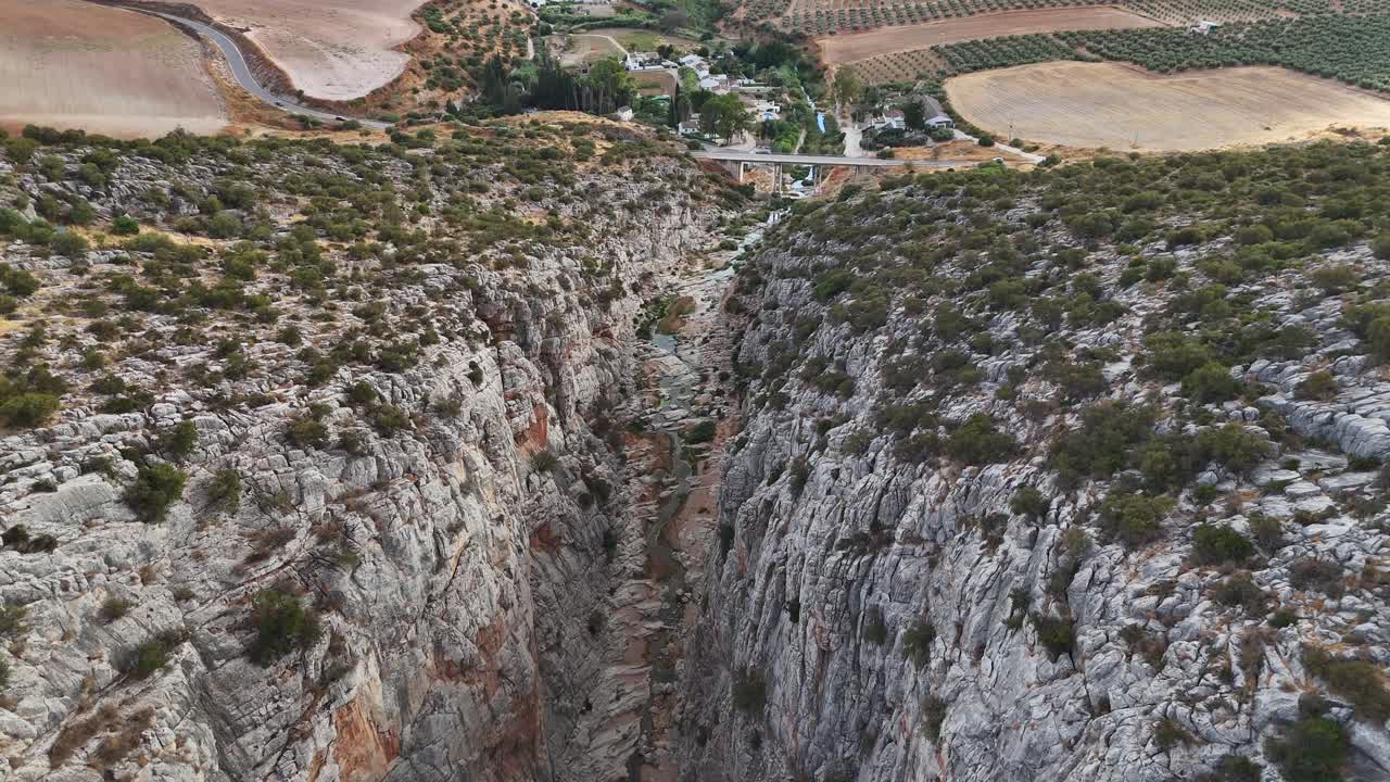 Ripresa aerea con avvicinamento lento verso una vetta rocciosa baciata dal sole in Andalusia. Toni caldi dell'ocra dominano l'inquadratura mentre il drone mantiene l'altitudine rivelando la profondità della valle sottostante.