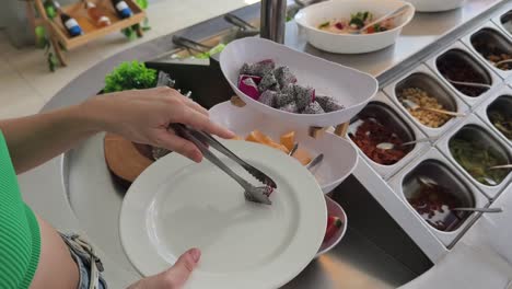 una mujer se sirve fruta de dragón en una barra de ensaladas.