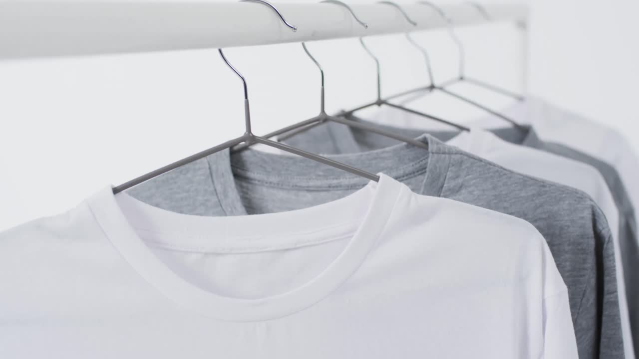 Video of white and grey t shirts on hangers and copy space on white background