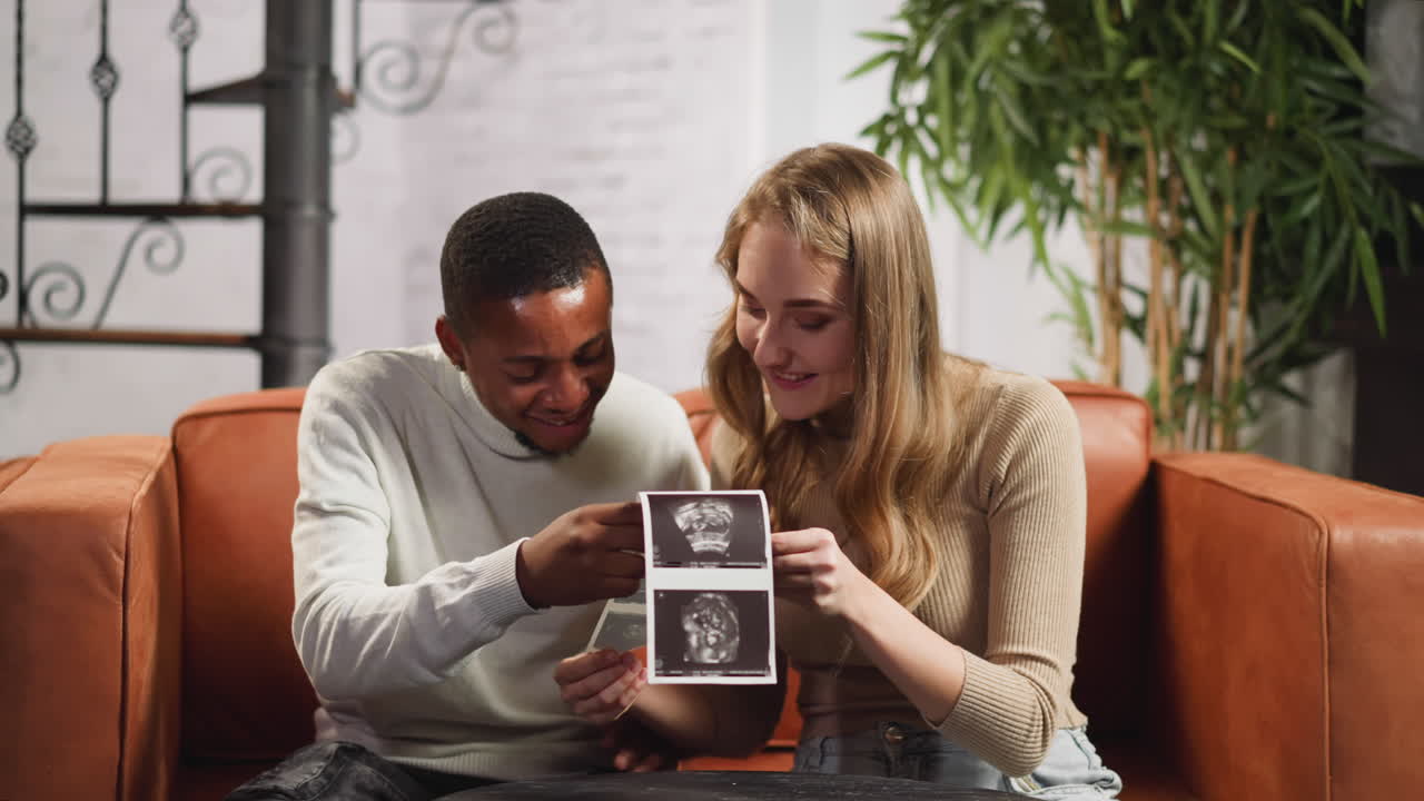 Family of black man and white lady with ultrasound pictures