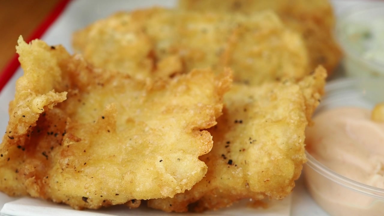 Primer plano de filetes de pescado fritos dorados y crujientes con salsas para mojar
