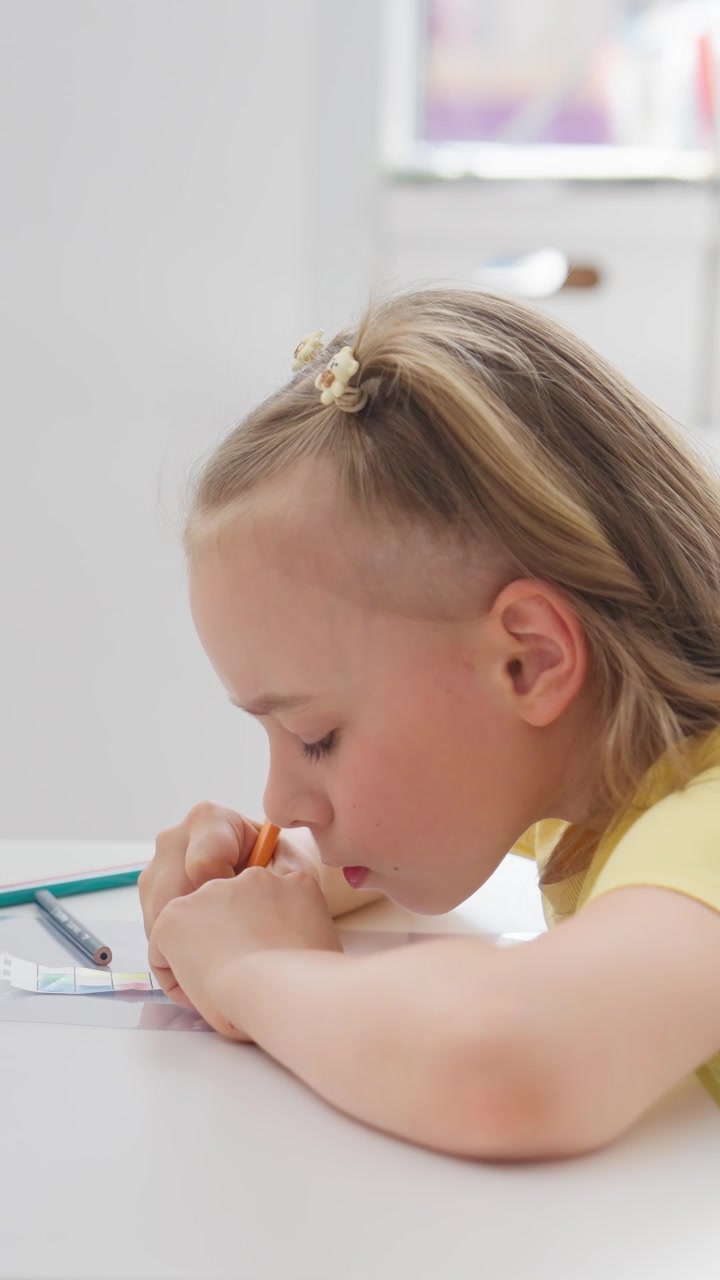 Bambina concentrata che disegna su carta con una matita