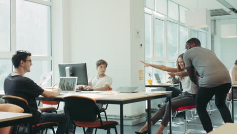 happy friends moving on chair around coworking. black man running from office.