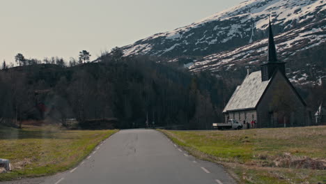 slow dolly toward a church in the countryside of vestlands surrounded by snow-capped mountains