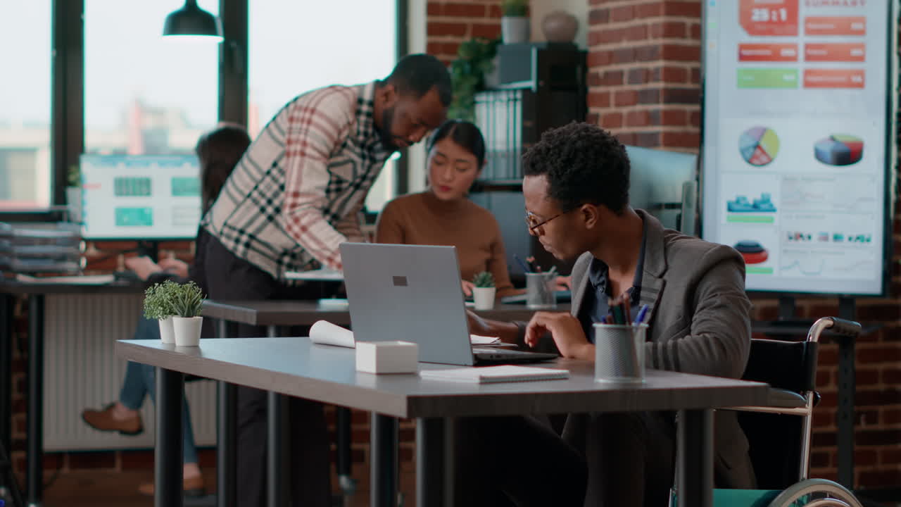 Businessman in wheelchair looking at charts analysis on laptop
