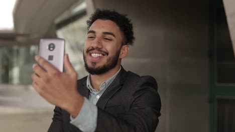 Cheerful-man-with-bristle-talking-on-smartphone-outdoor