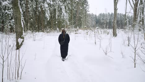 invierno, una profunda nevada en el suelo como una mujer joven envuelta camina en