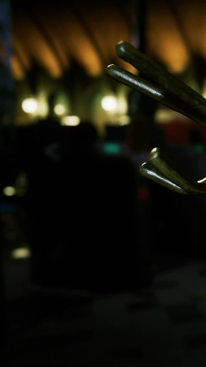 Un gancio di metallo è appeso in un'area bar scarsamente illuminata con figure sfocate sullo sfondo.