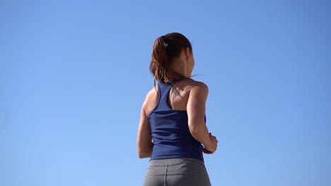 back view of sporty girl jogging at sunny day