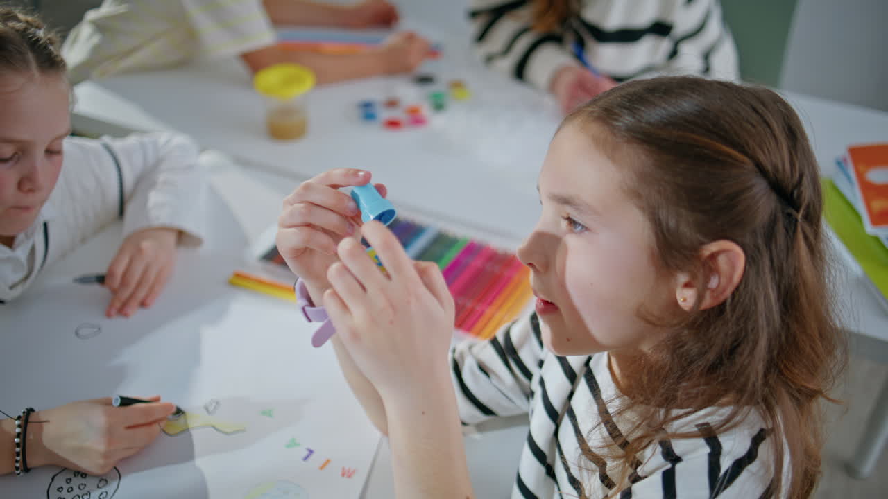 Funny girl holding stamp creating art in school class room closeup. Kid drawing