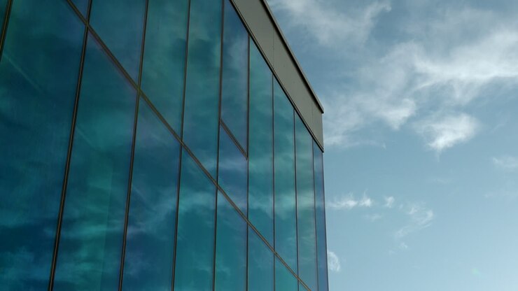 Riflesso del cielo blu e delle nuvole sulla facciata in vetro di un moderno edificio