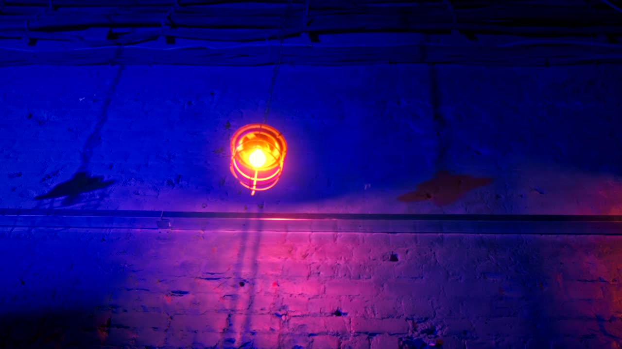 다른 방향으로 흔들리는 긴 사슬에 인 철 랜턴. 네온 조명