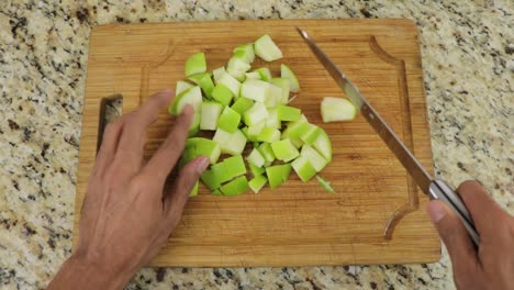 pov cortando la manzana verde en cubos con un cuchillo en la tabla de cortar