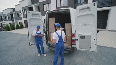 two young workers of removal company are loading boxes and furniture into a minibus