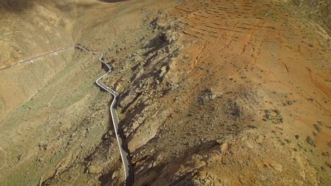 vista aérea de un coche conduciendo en una sinuosa carretera de montaña en fuerteventura.