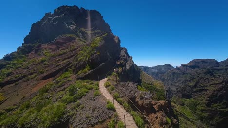 Pico-do-Pico-hiking-trail-with-handrail-and-footpath-along-steep-rugged-terrain-of-Madeira,-Portugal