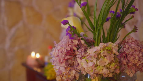 una toma de panorámica dinámica captura un ambiente calmante y acogedor con un ramo único de flores florales ecuatorianas que incluyen claveles, lirios y otras flores en contraste con una pared de piedra natural