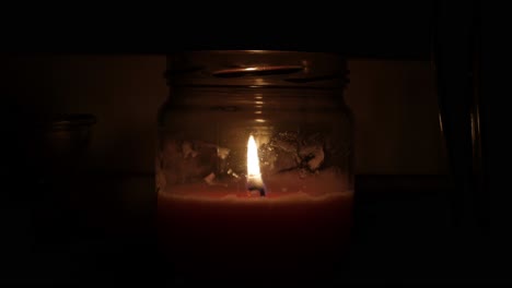 una toma amplia de una luz de vela en movimiento en una habitación oscura y silenciosa en la noche