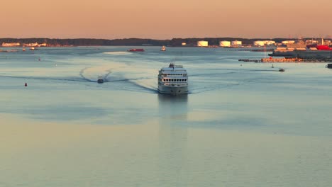 Cruise-ship-sailing-at-sunset-with-wake-patterns-on-calm-sea-waters-during-sunrise