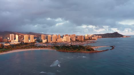 wide descending aerial shot of magic beach in honolulu, hawaii at sunset