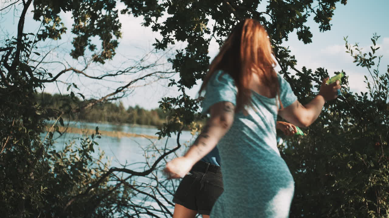 Friends Playing Water Guns by the Lake