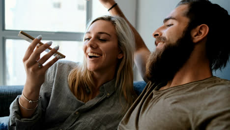 Couple-using-mobile-phone-and-laptop-in-living-room-4k