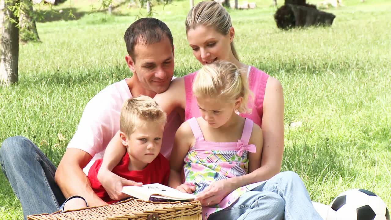 Genitori e bambini che leggono al parco
