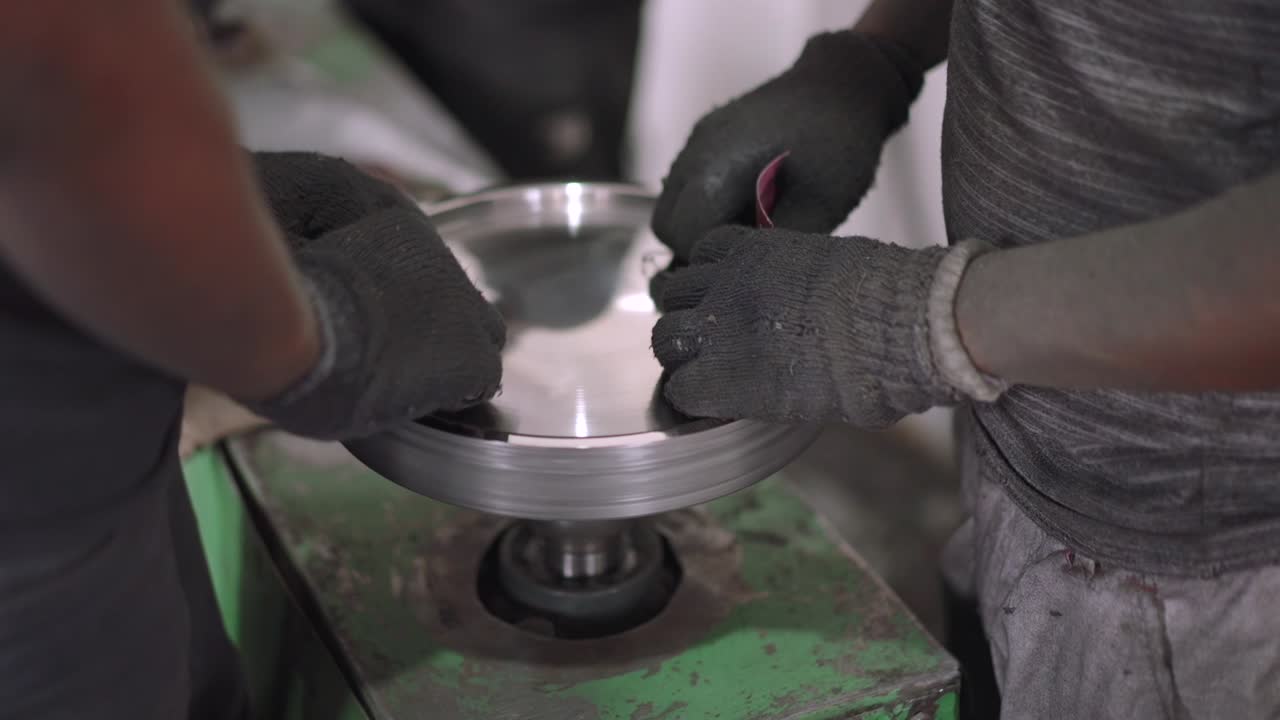 Using a belt sander to produce steel pan cookware in a factory