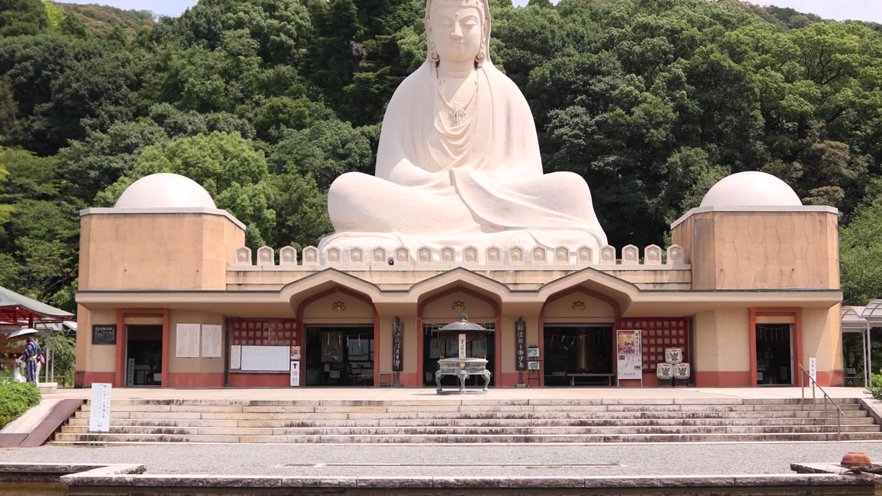 Cảnh nhìn từ phía trước khu tưởng niệm Ryozen Kannon ở Kyoto, với kiến trúc Phật giáo màu nhạt phản chiếu trong một ao nước tĩnh lặng và được bao quanh bởi cây xanh tại quận Higashiyama lịch sử, Nhật Bản.