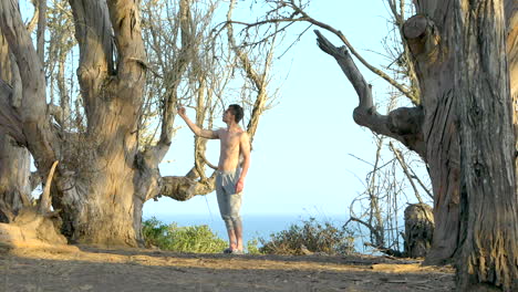 Joven-Sin-Camisa-Tomando-Una-Selfie-Con-Su-Teléfono-Inteligente-En-Los-Acantilados-Con-Vista-Al-Océano-Pacífico-Azul-En-Santa-Barbara,-California