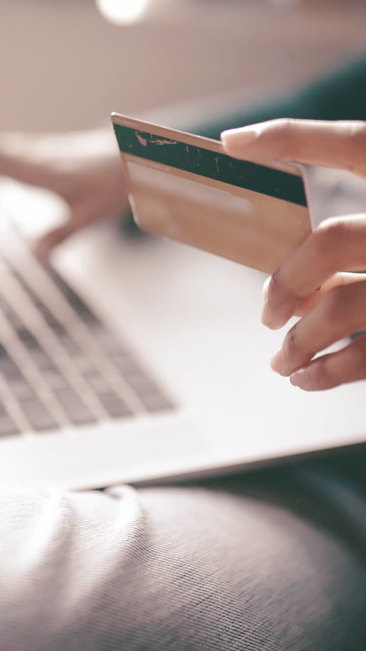 Primo piano di mani che tengono una carta di credito e digitano su un laptop