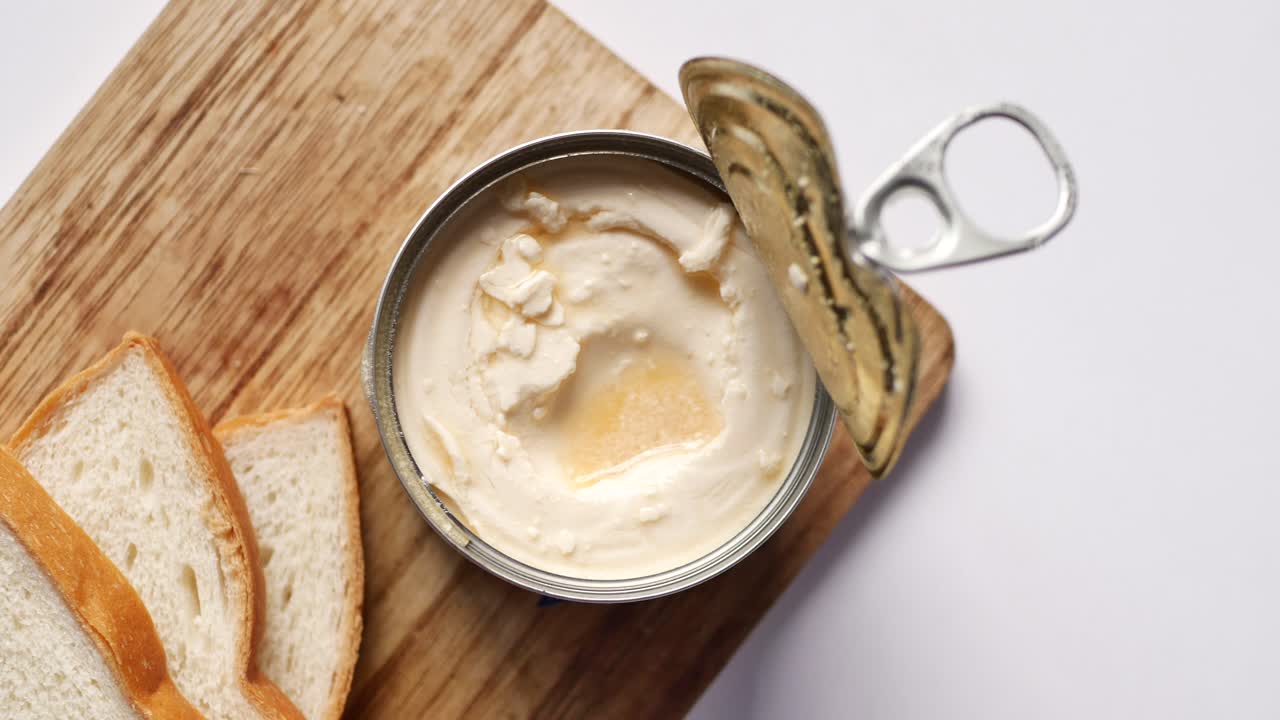 Barattolo aperto di burro cremoso con fette di pane