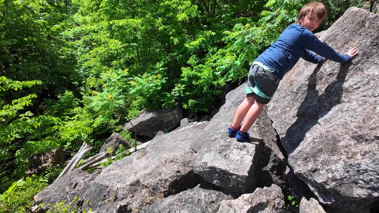 Young boy climbing on a rock face at Rattlesnake Point, Ontario, Canada