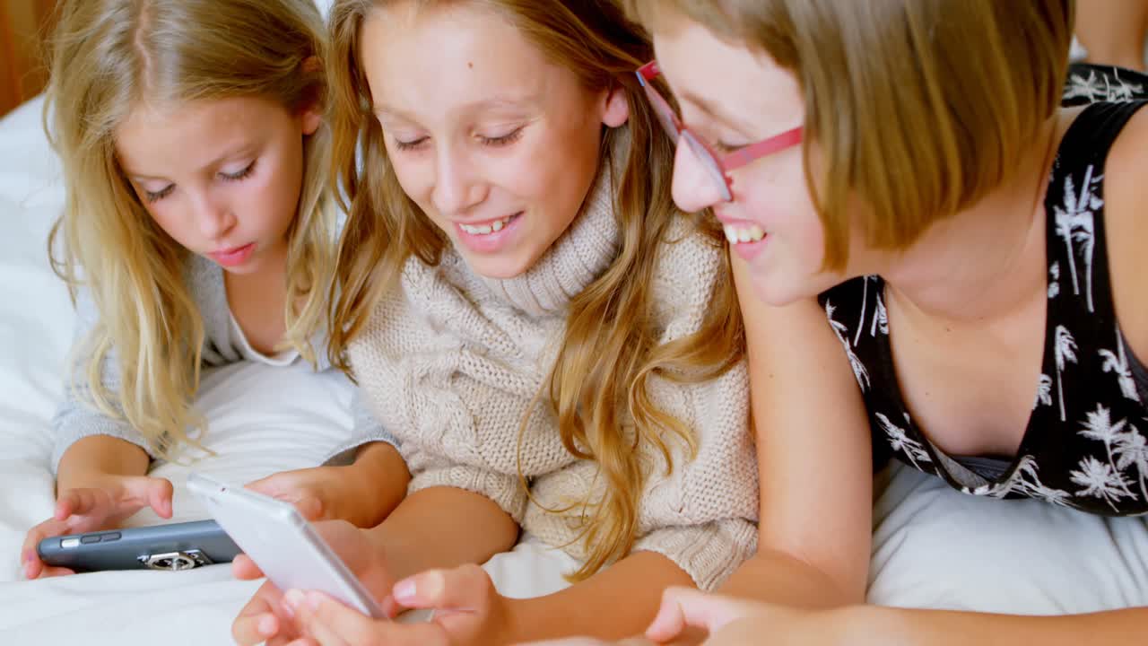 침실 4k에서 휴대폰을 사용하는 형제자매